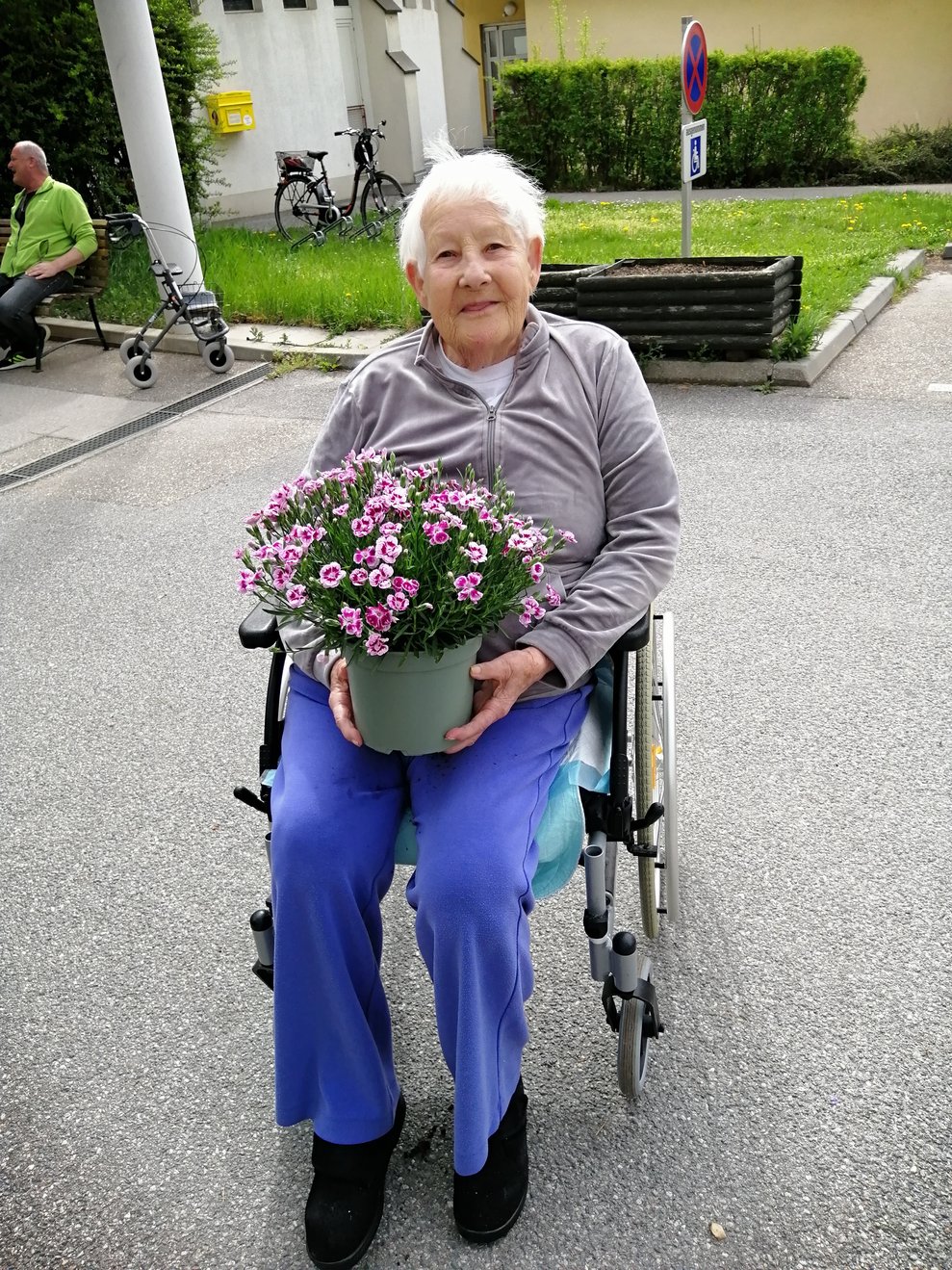 Eine Dame im Rollstuhl hält Blumen in den Händen. 