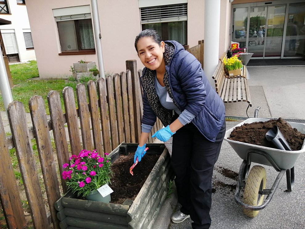 Eine Dame setzt Blumen in die Kisten. 