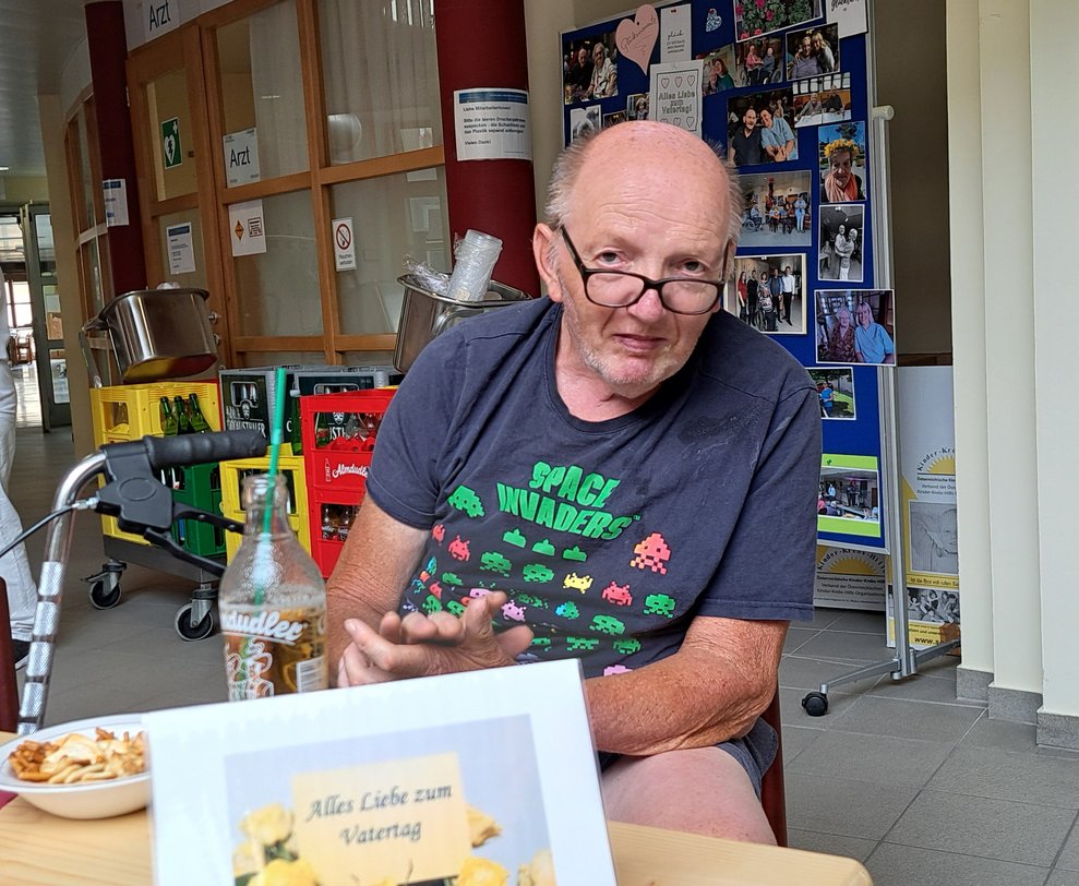 Ein Mann sitzt bei Tisch mit Knabberei und Getränk.