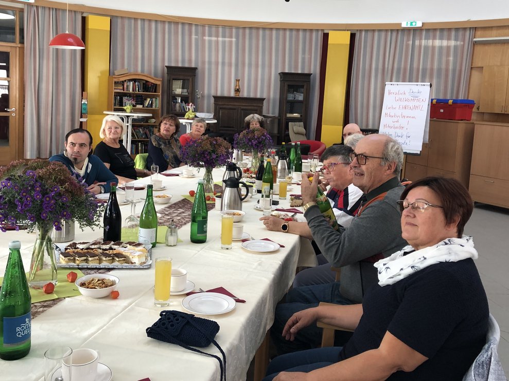 ehrenamtliche Mitarbeiterinnen und Mitarbeiter sitzen um den Tisch. 
