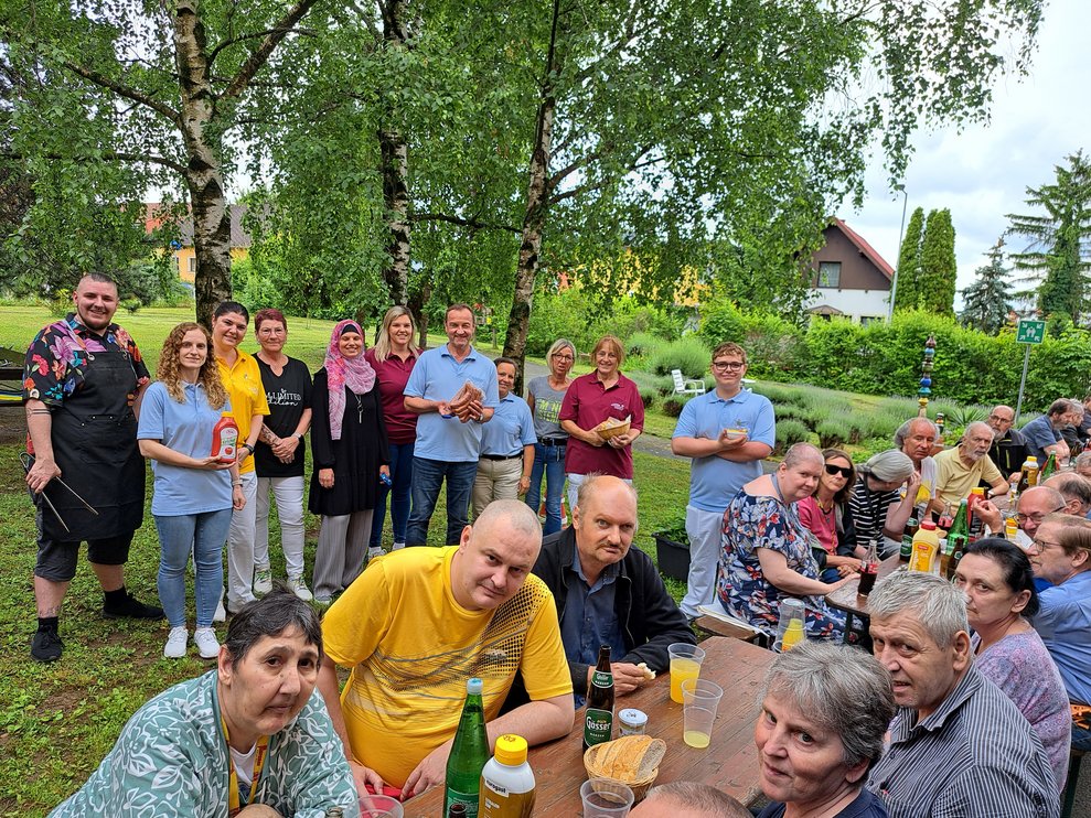 Mitarbeiter und Klienten bei der Grillerei. 